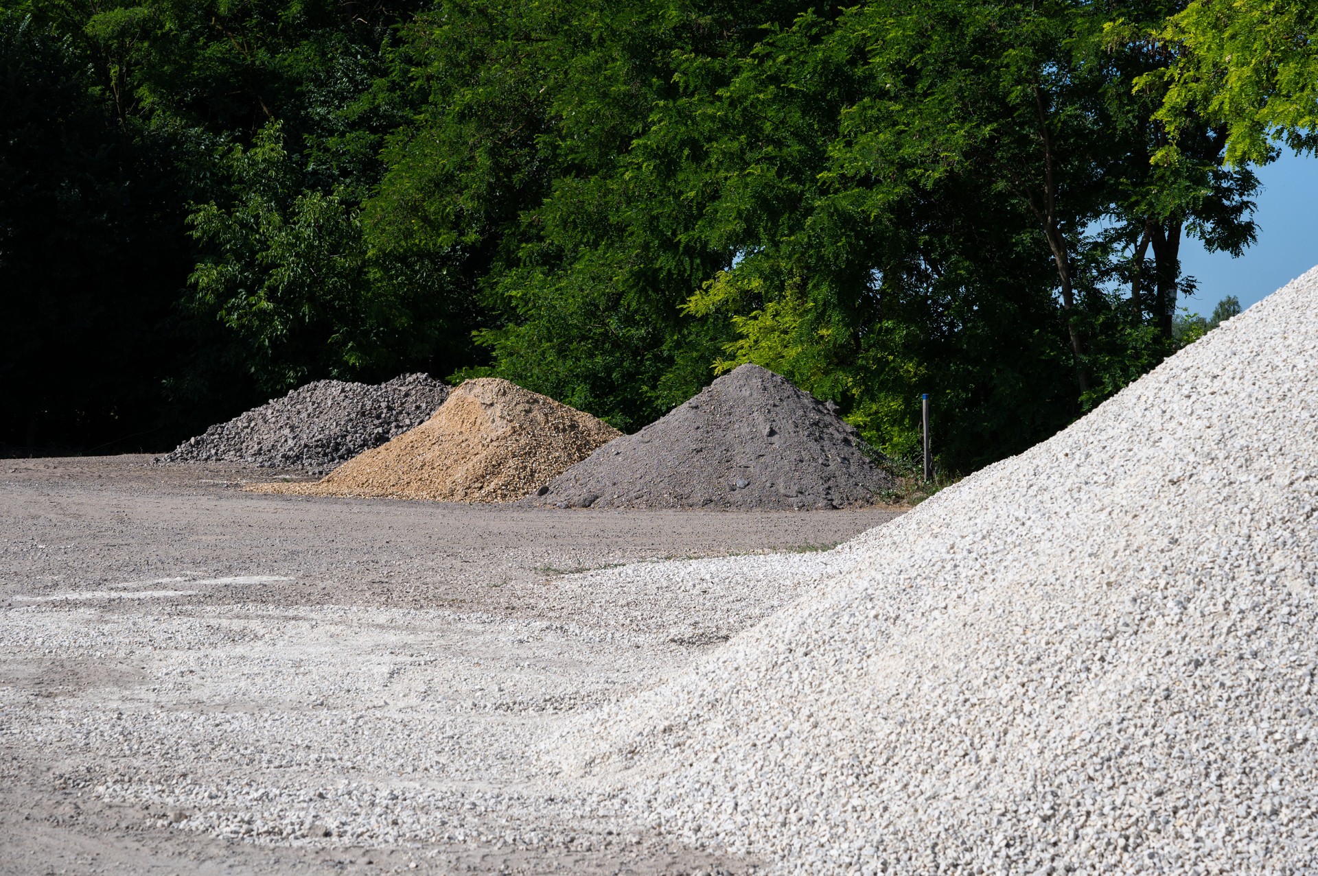 Gravel piles in an open depot under a clear blue sky